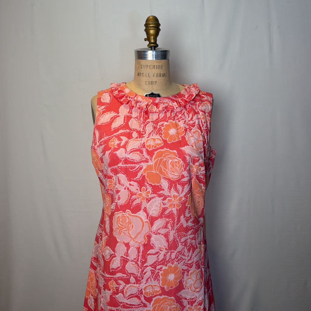 A pink & peach floral mod dress on a dress form in front of a white wall.