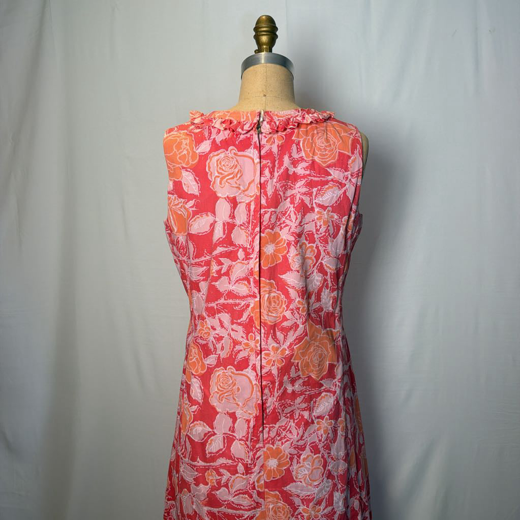 A pink & peach floral mod dress on a dress form in front of a white wall.
