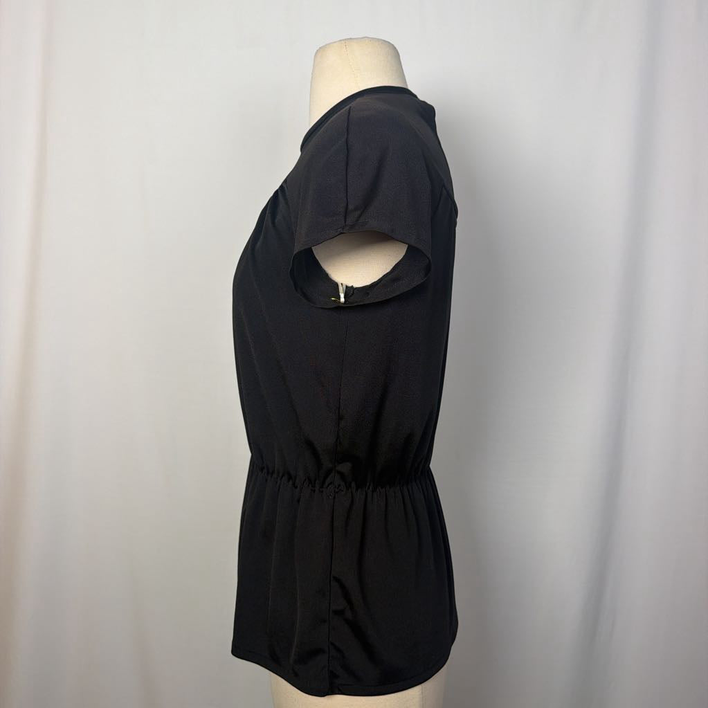 A black short-sleeve blouse with a unique cutout on the upper sleeve and a gathered elastic waist, displayed on a mannequin torso against a white fabric backdrop.