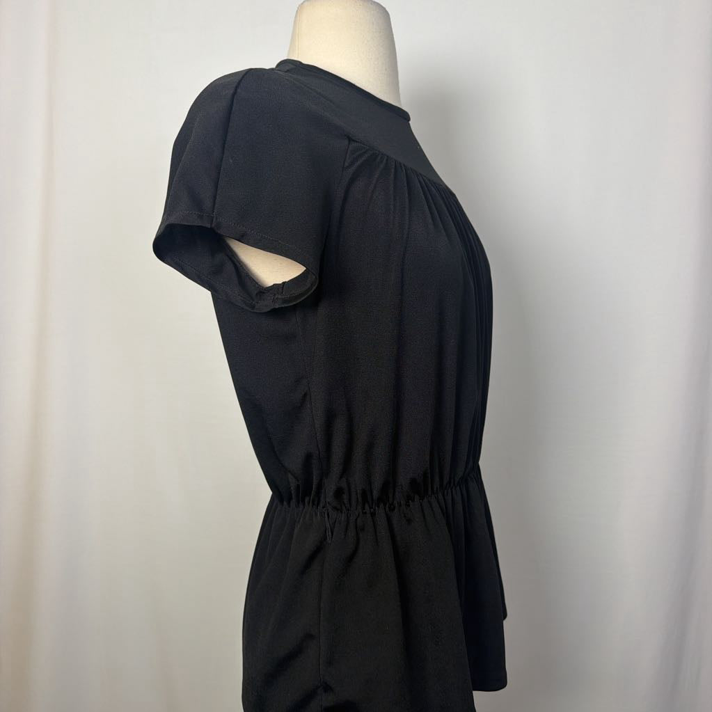 A black short-sleeve peplum dress displayed on a mannequin torso against a light gray fabric backdrop.