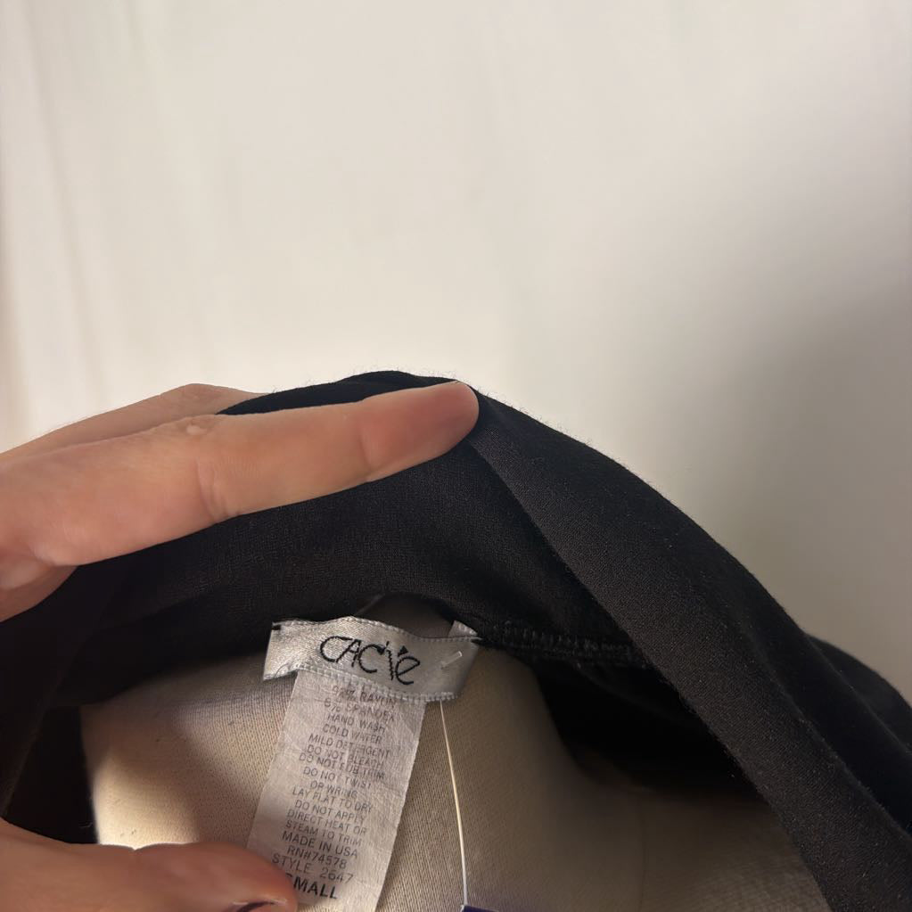 A hand holding the inside of a shirt and showing the internal brand tag.