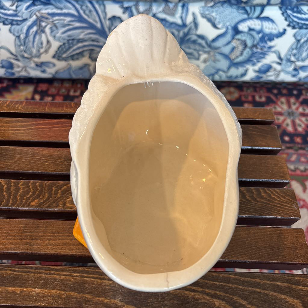 The inside of a white ceramic duck shaped cookie jar sitting on a wooden table in a room setting.