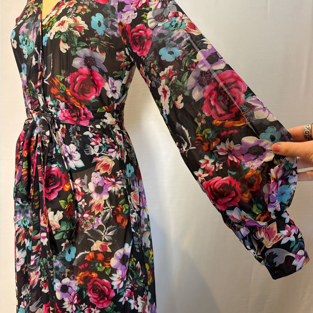 A floral maxi dress on a mannequin in front of a white wall.
