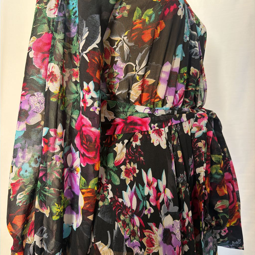 A floral maxi dress on a mannequin in front of a white wall.