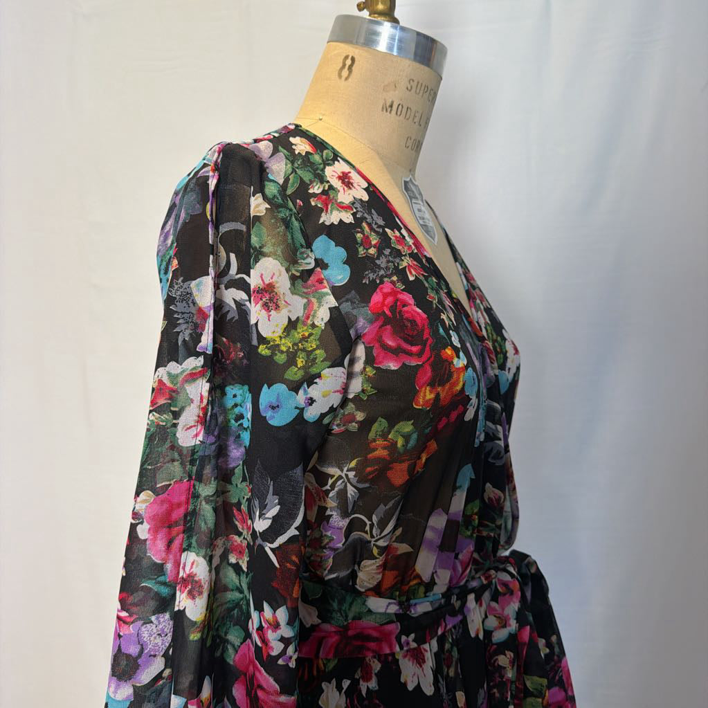A floral maxi dress on a mannequin in front of a white wall.