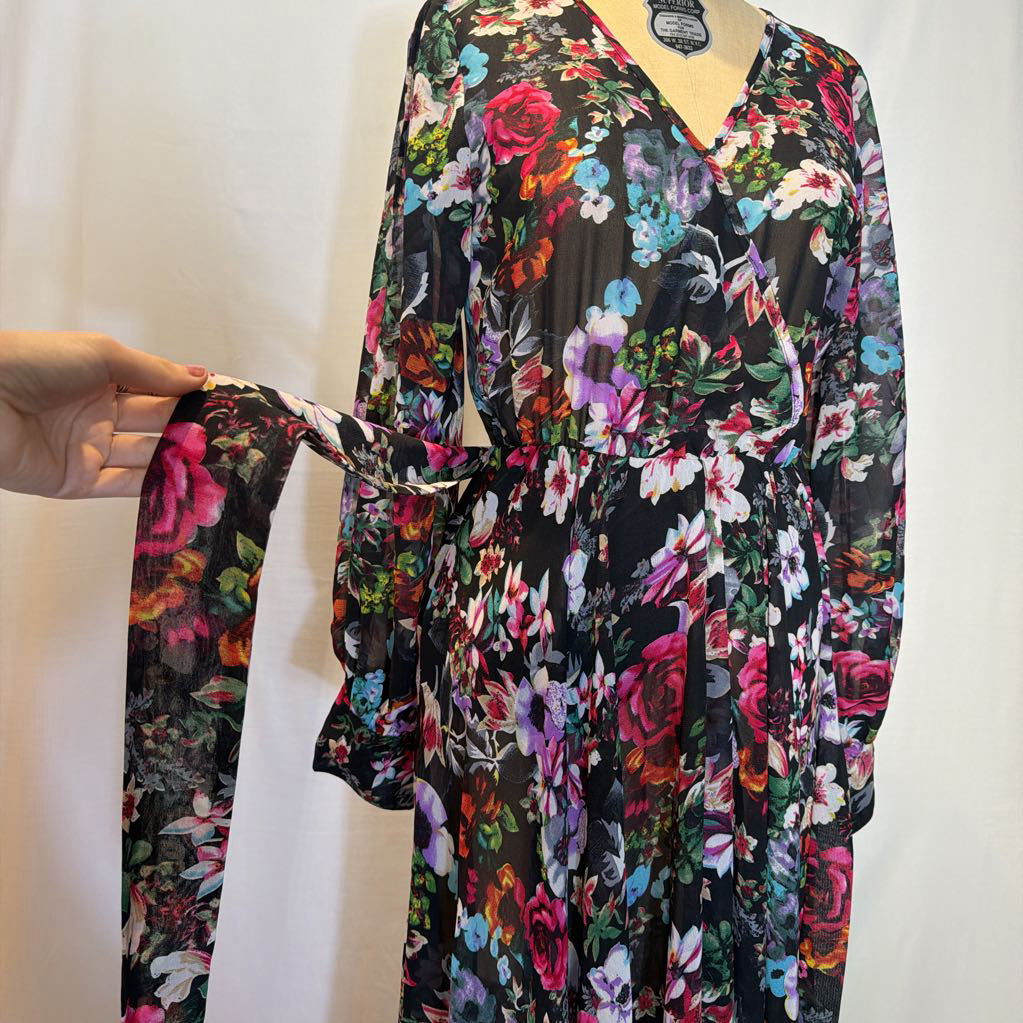 A floral maxi dress on a mannequin in front of a white wall.