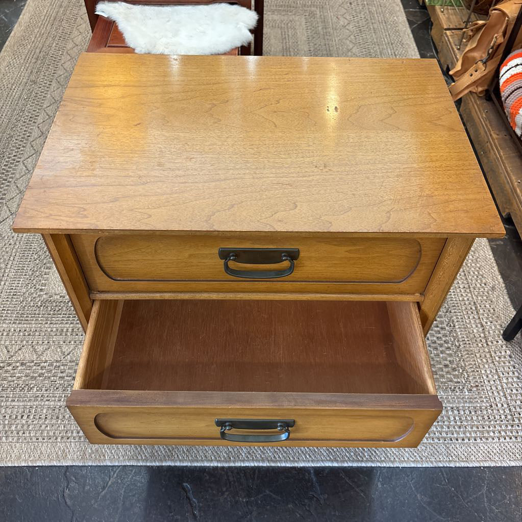 A wooden nightstand with drawers in a store setting.