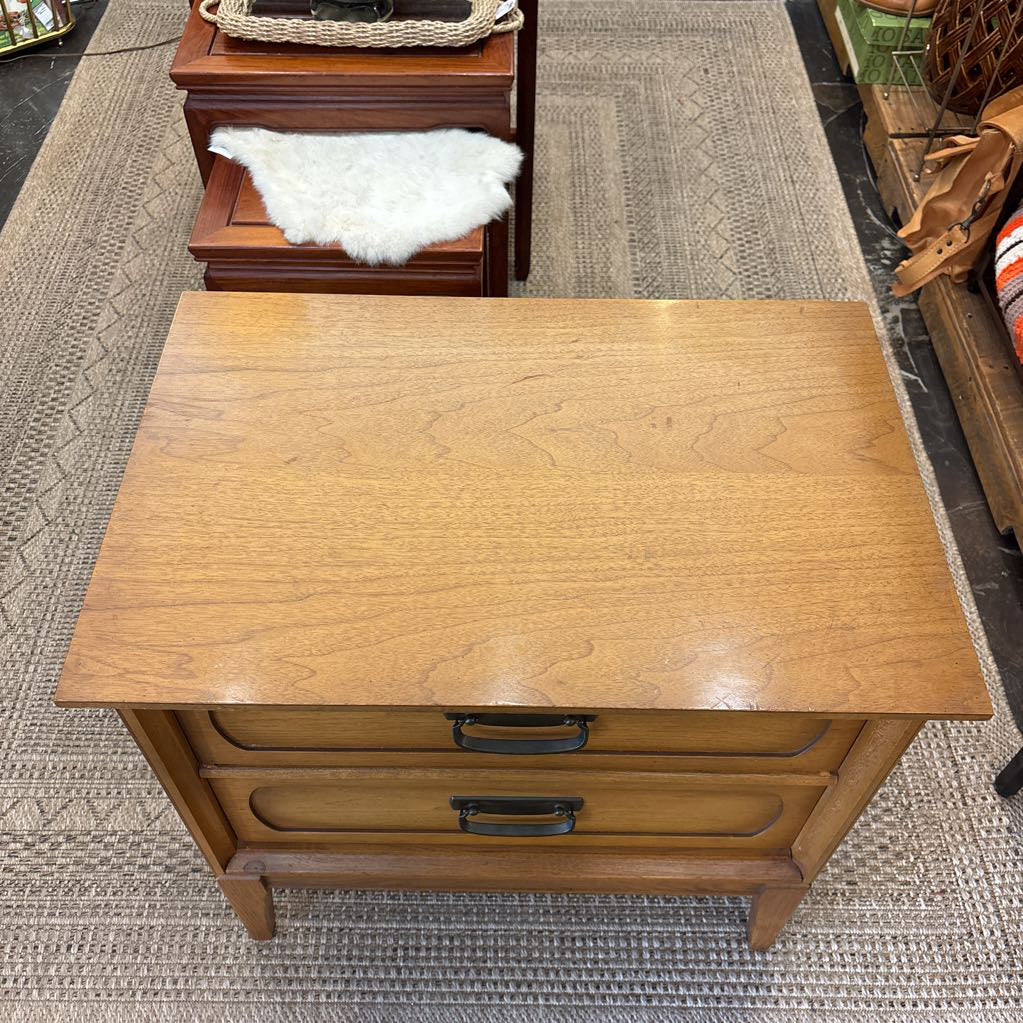 A wooden nightstand with drawers in a store setting.
