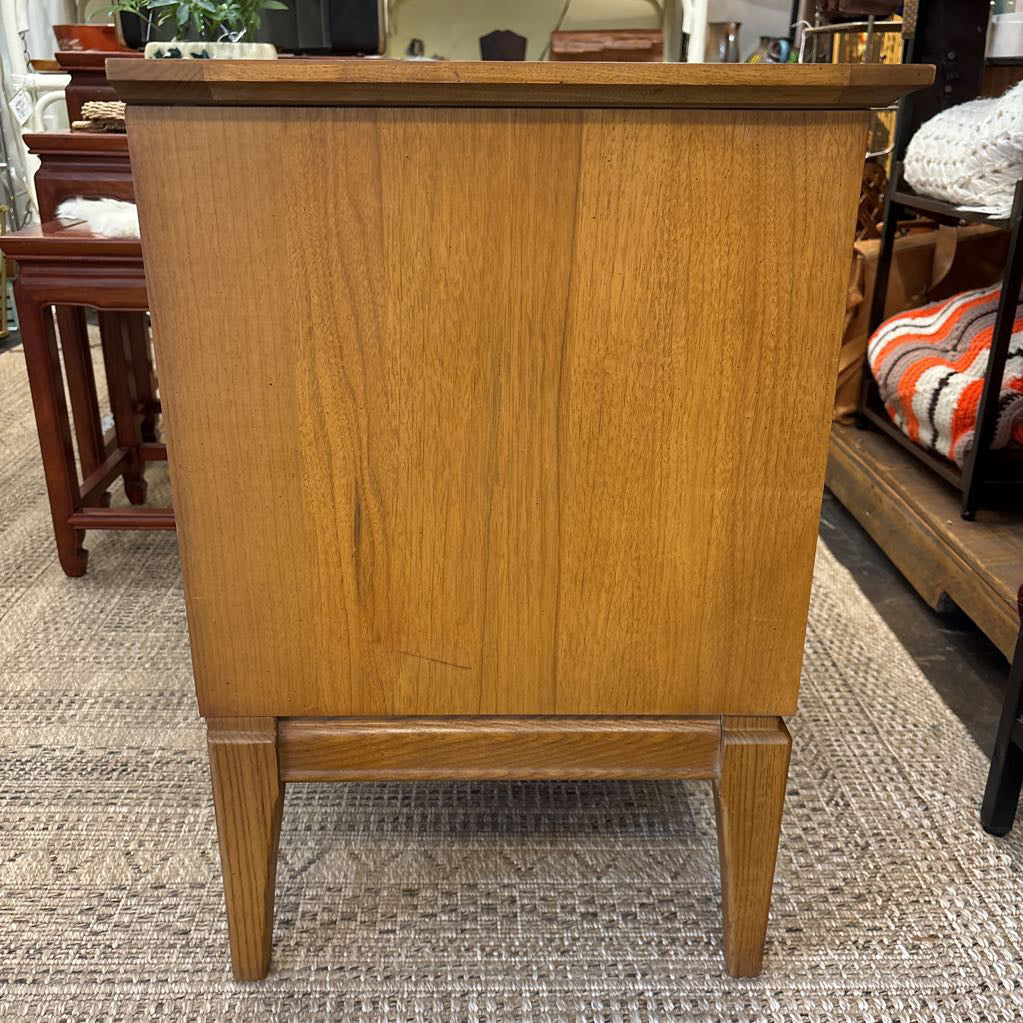 A wooden nightstand with drawers in a store setting.