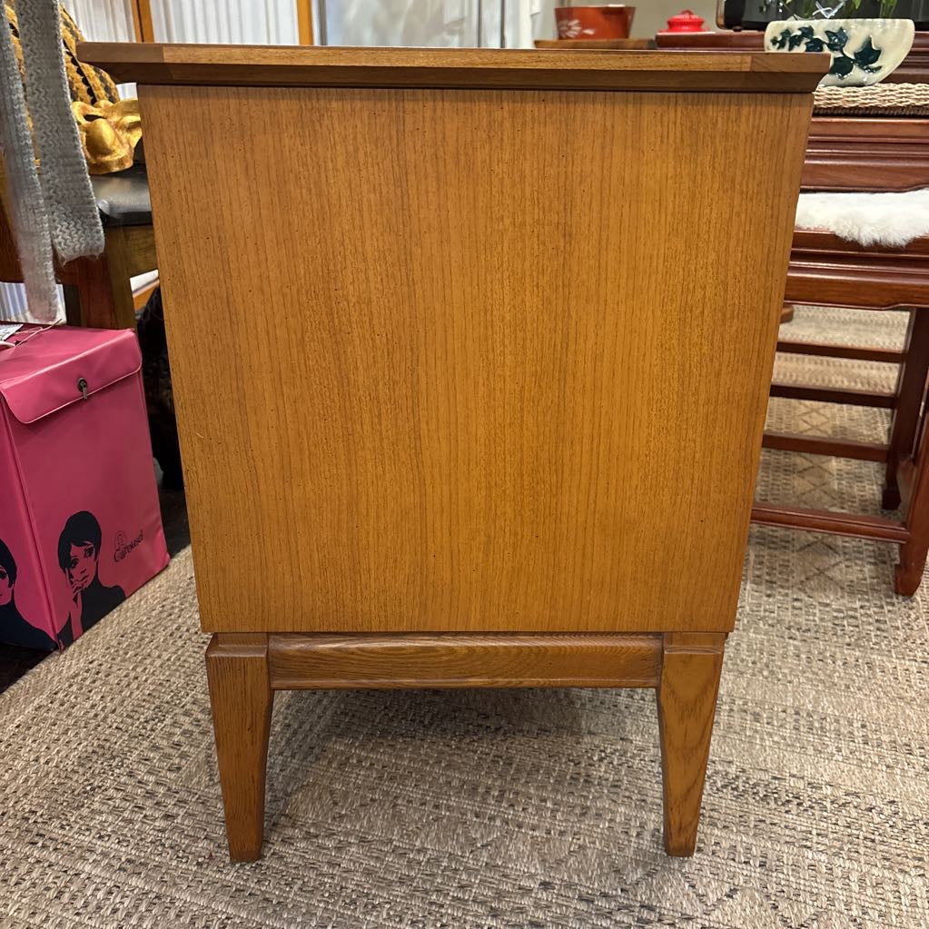 A wooden nightstand with drawers in a store setting.