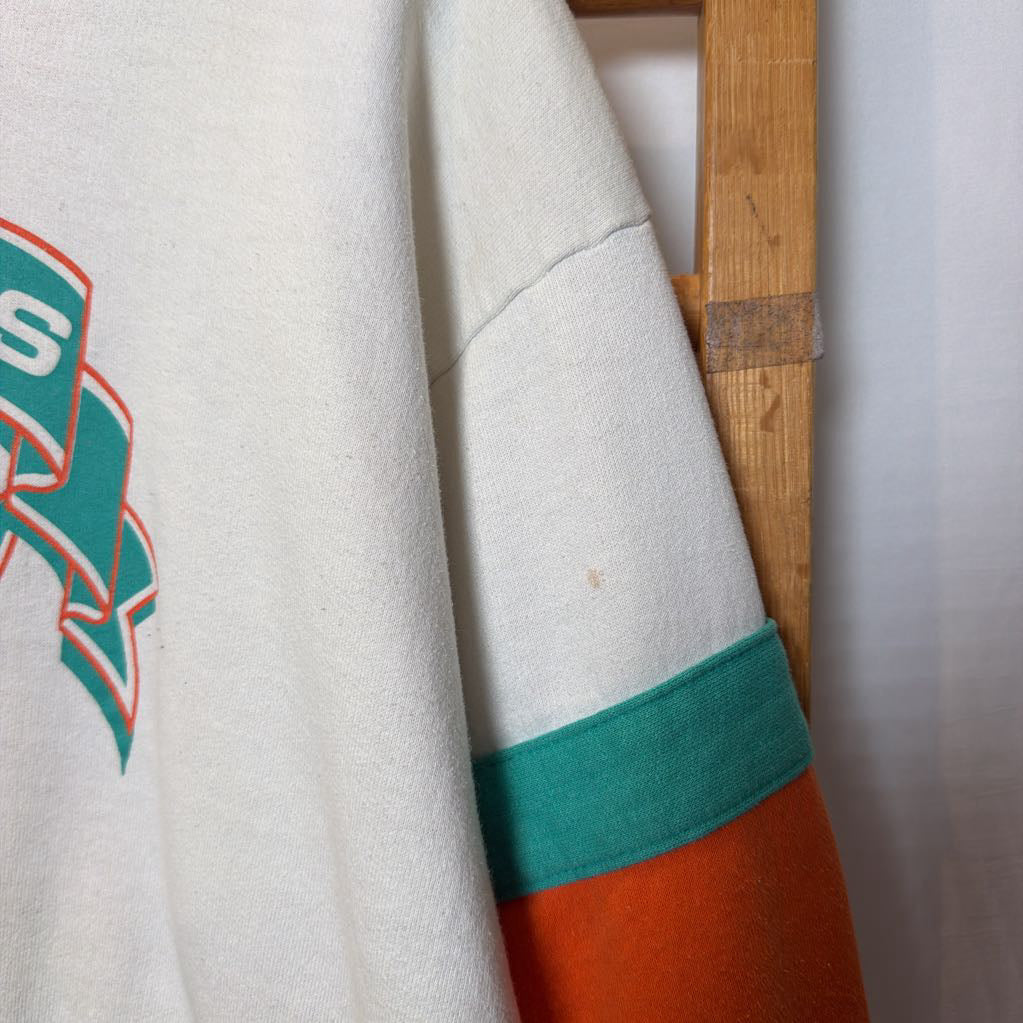 A white, orange, and turquoise Miami Dolphins branded sweatshirt on a wooden rack.