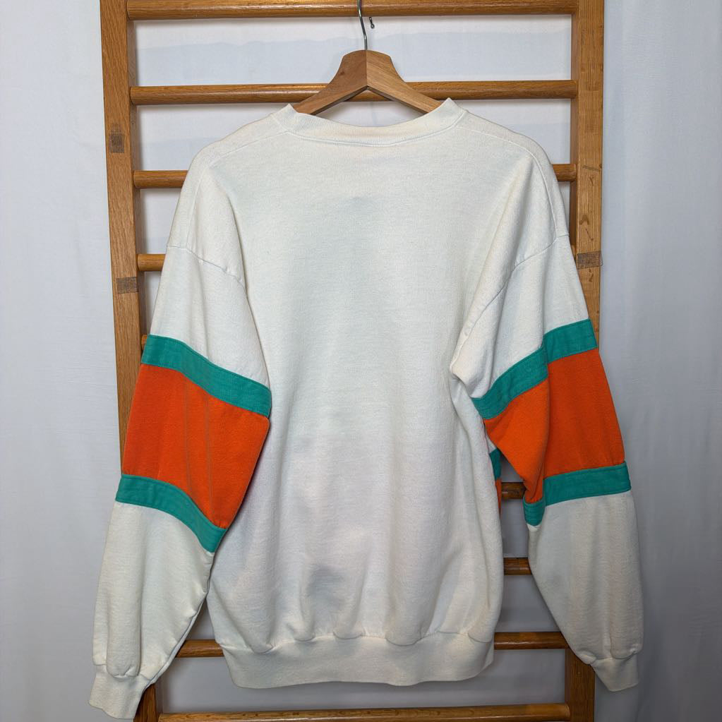 A white, orange, and turquoise Miami Dolphins branded sweatshirt on a wooden rack.