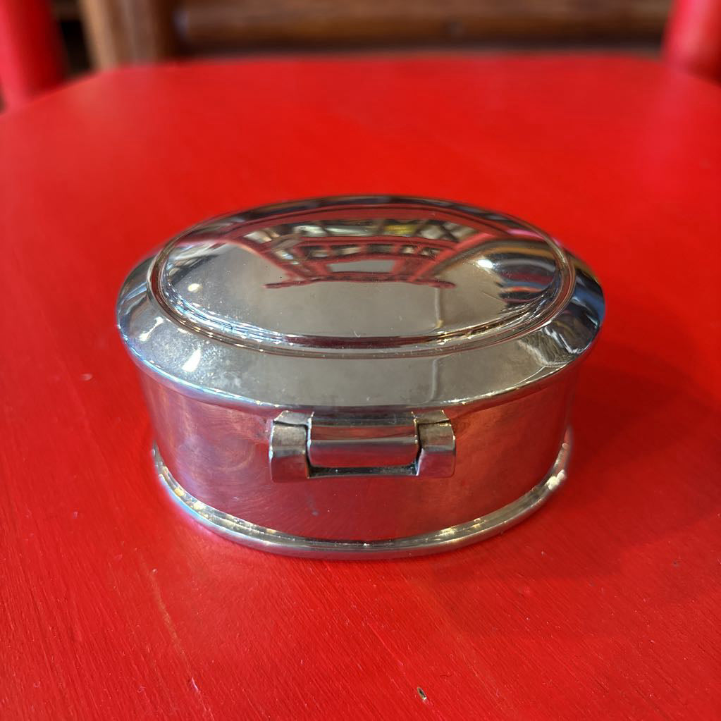 A silver jewelry box on a red surface.