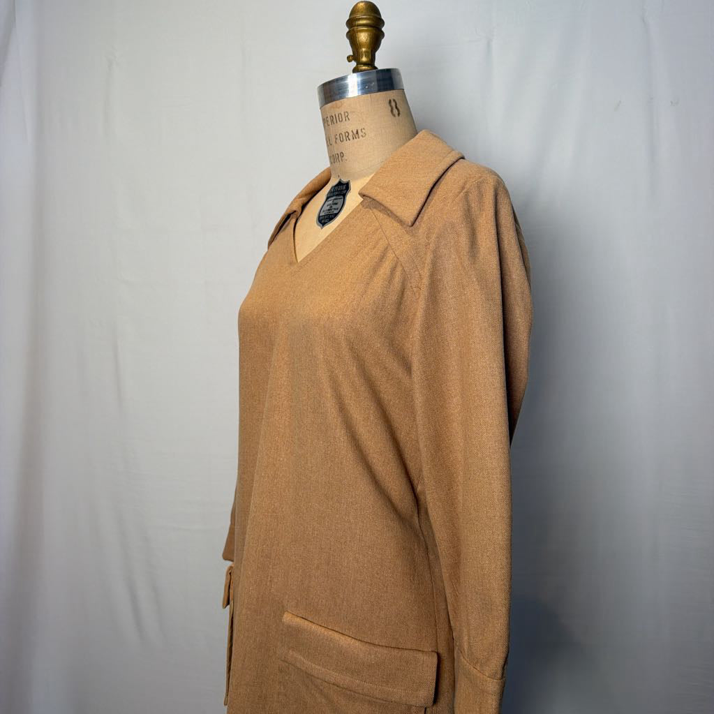 A long sleeve tan wool dress on a mannequin in front of a white wall.