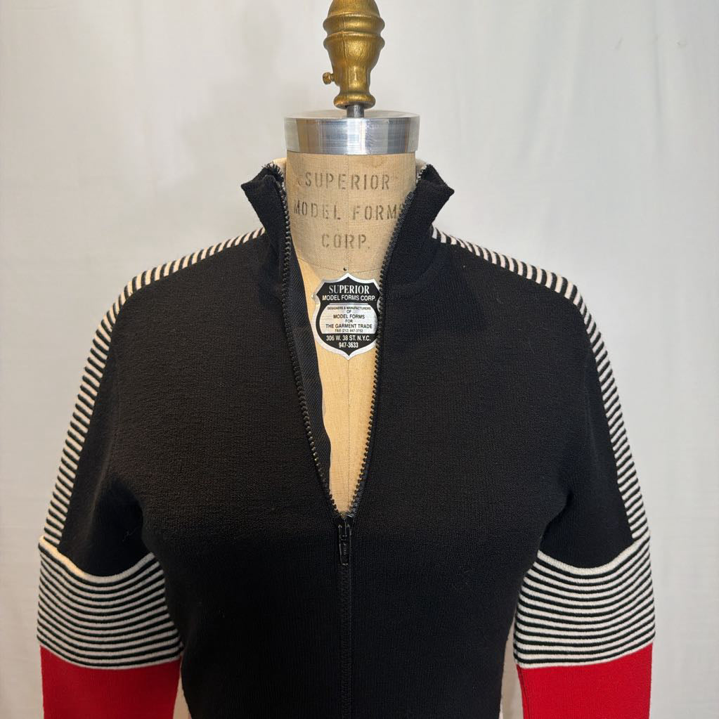 A black, red, and white color block zip-up jacket on a mannequin in front of a white wall.