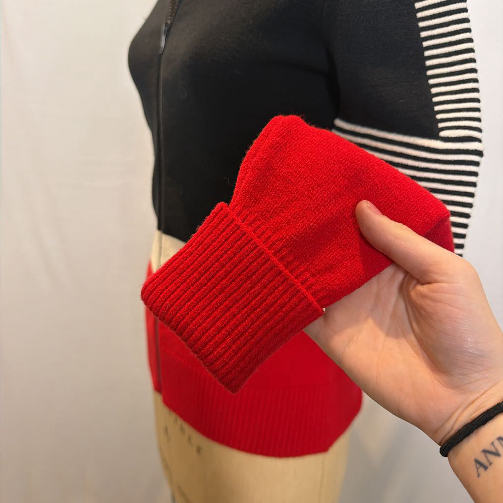 A black, red, and white color block zip-up jacket on a mannequin in front of a white wall.