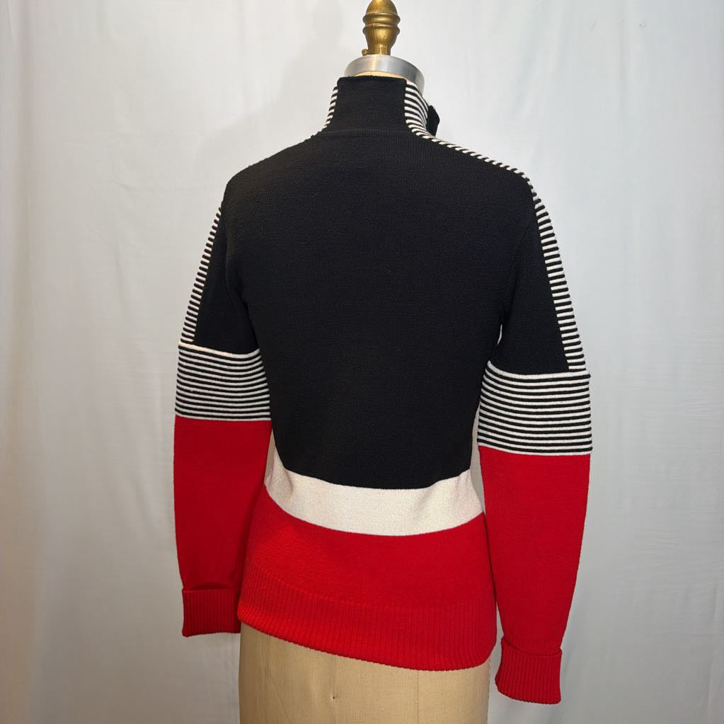 A black, red, and white color block zip-up jacket on a mannequin in front of a white wall.