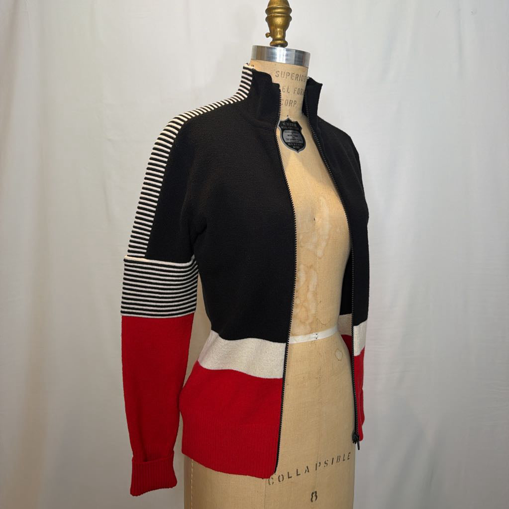 A black, red, and white color block zip-up jacket on a mannequin in front of a white wall.