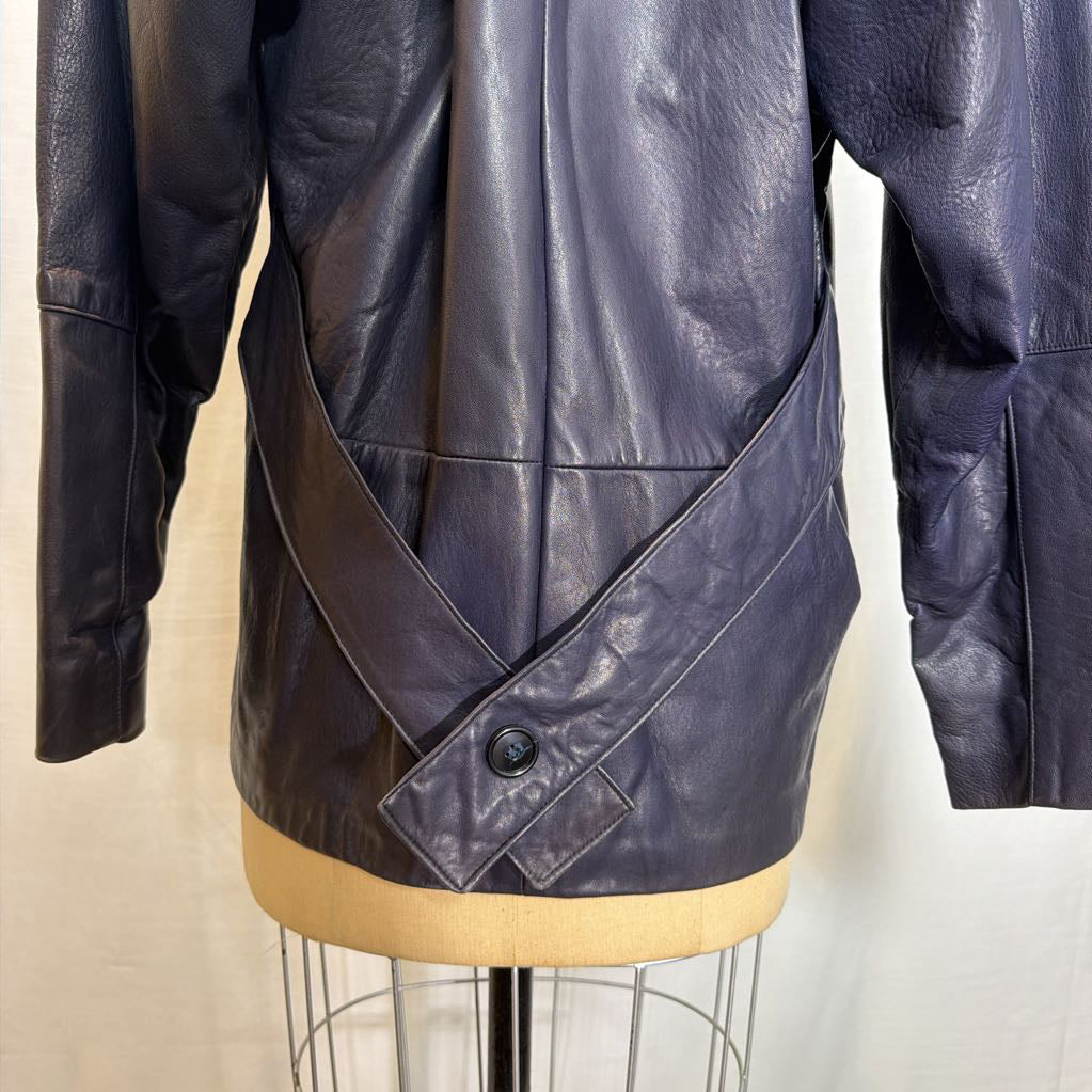 A navy leather trench jacket on a mannequin in front of a white wall.