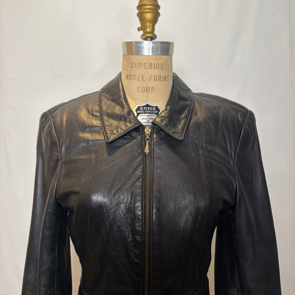 A black zip-up leather jacket on a mannequin in front of a white wall.