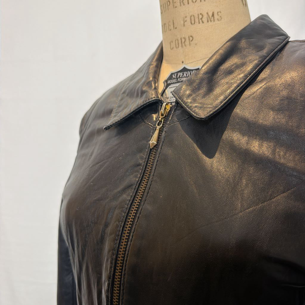 A black zip-up leather jacket on a mannequin in front of a white wall.