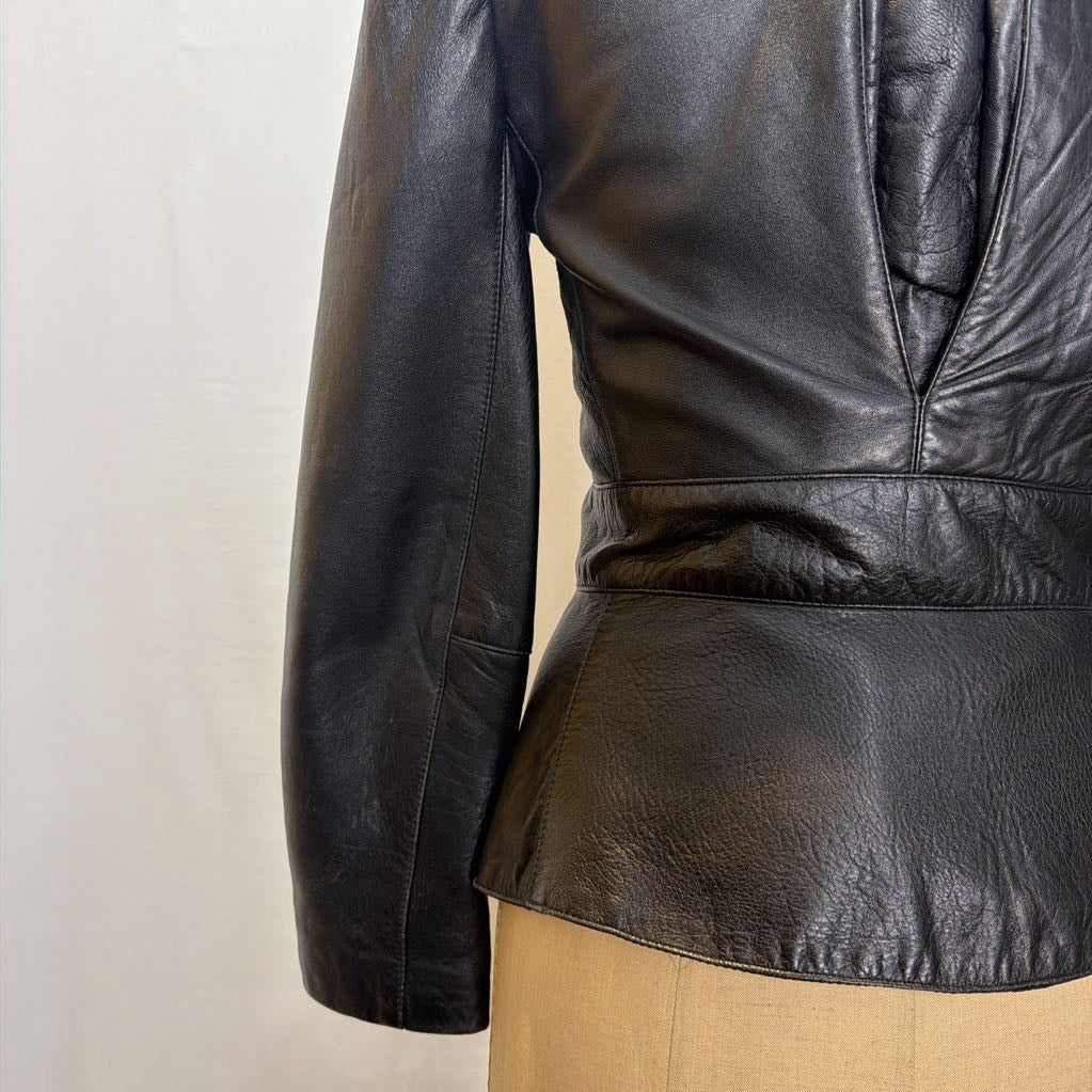 A black zip-up leather jacket on a mannequin in front of a white wall.