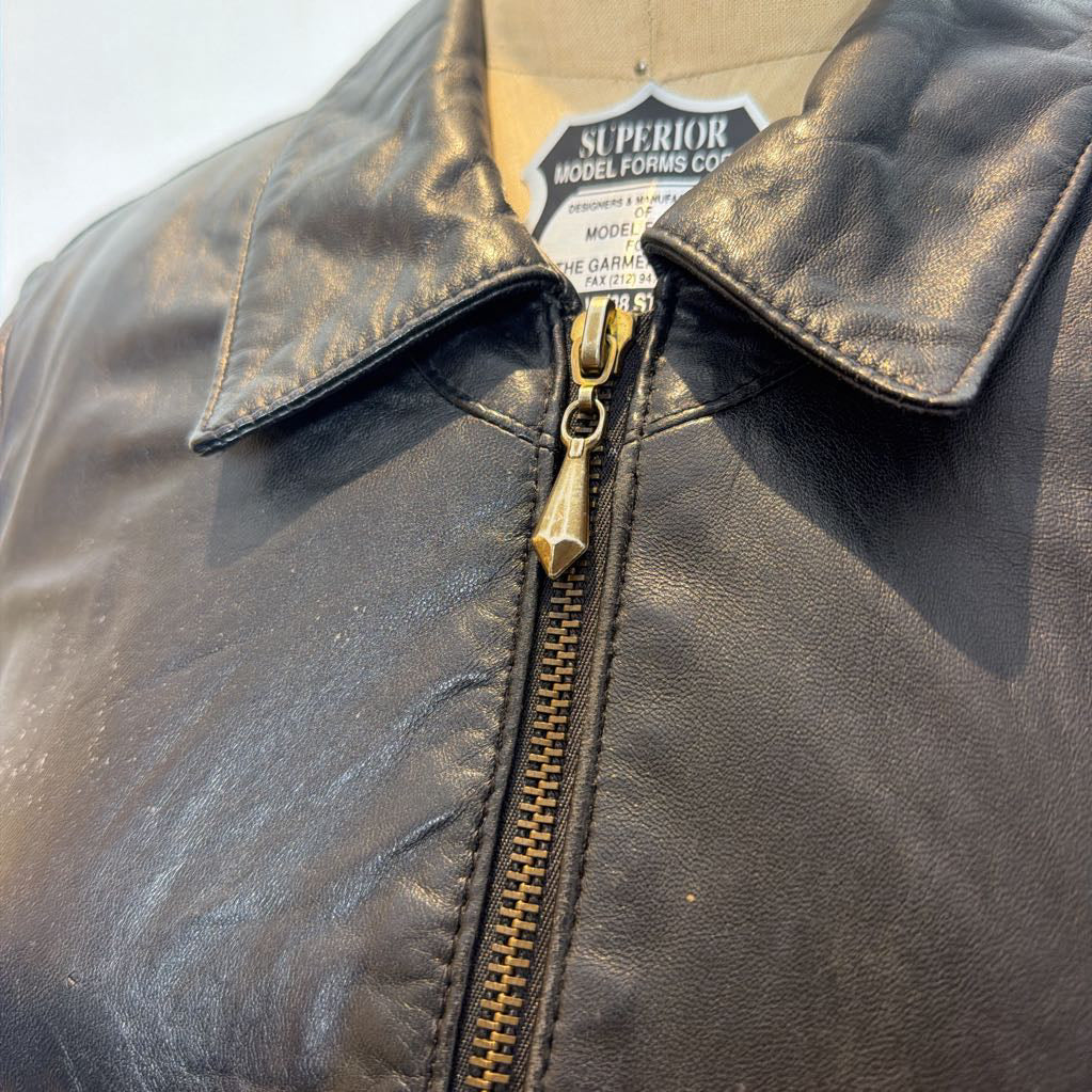 A black zip-up leather jacket on a mannequin in front of a white wall.
