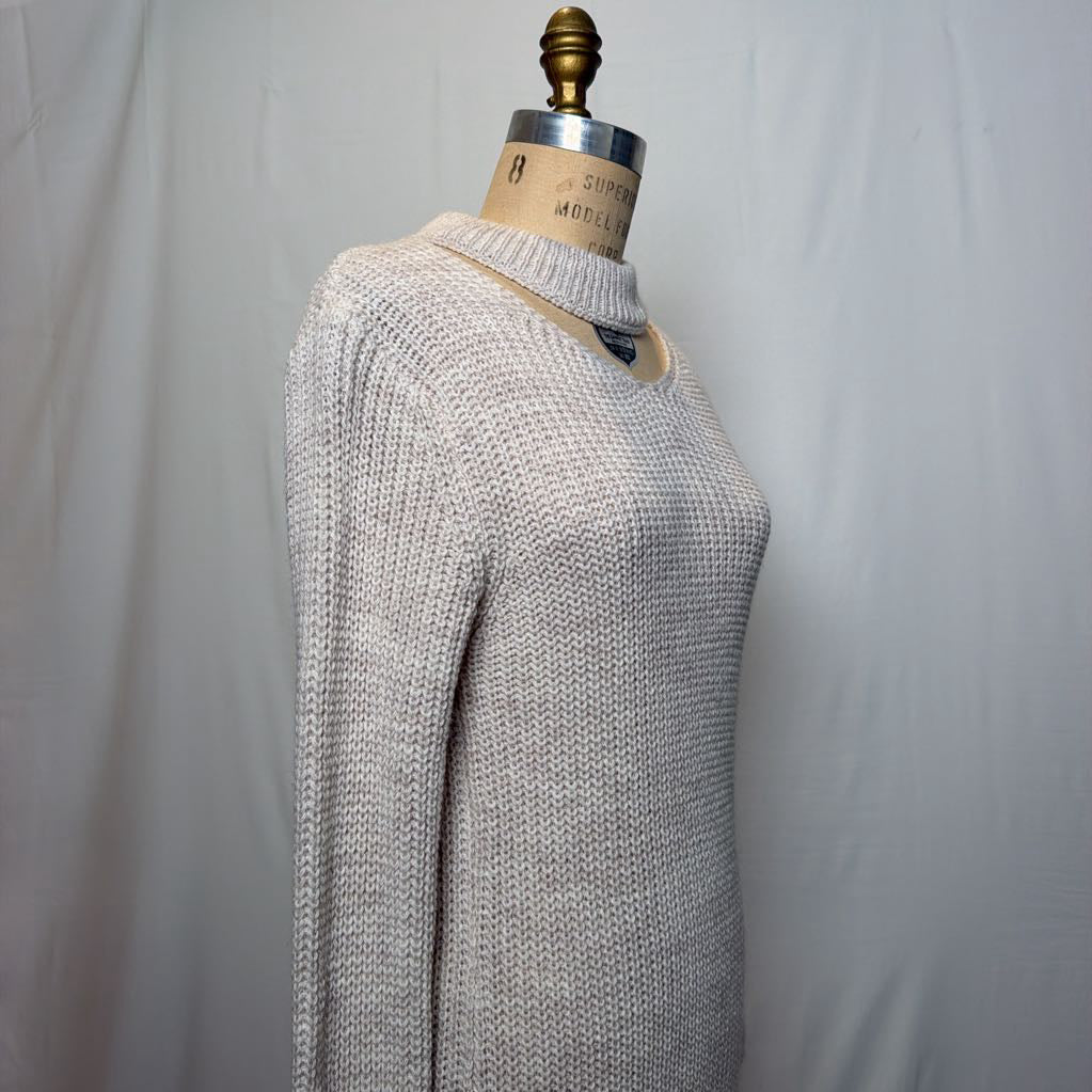 A white knit dress with an open neck and a slit on the bottom. It's on a mannequin in front of a white wall.