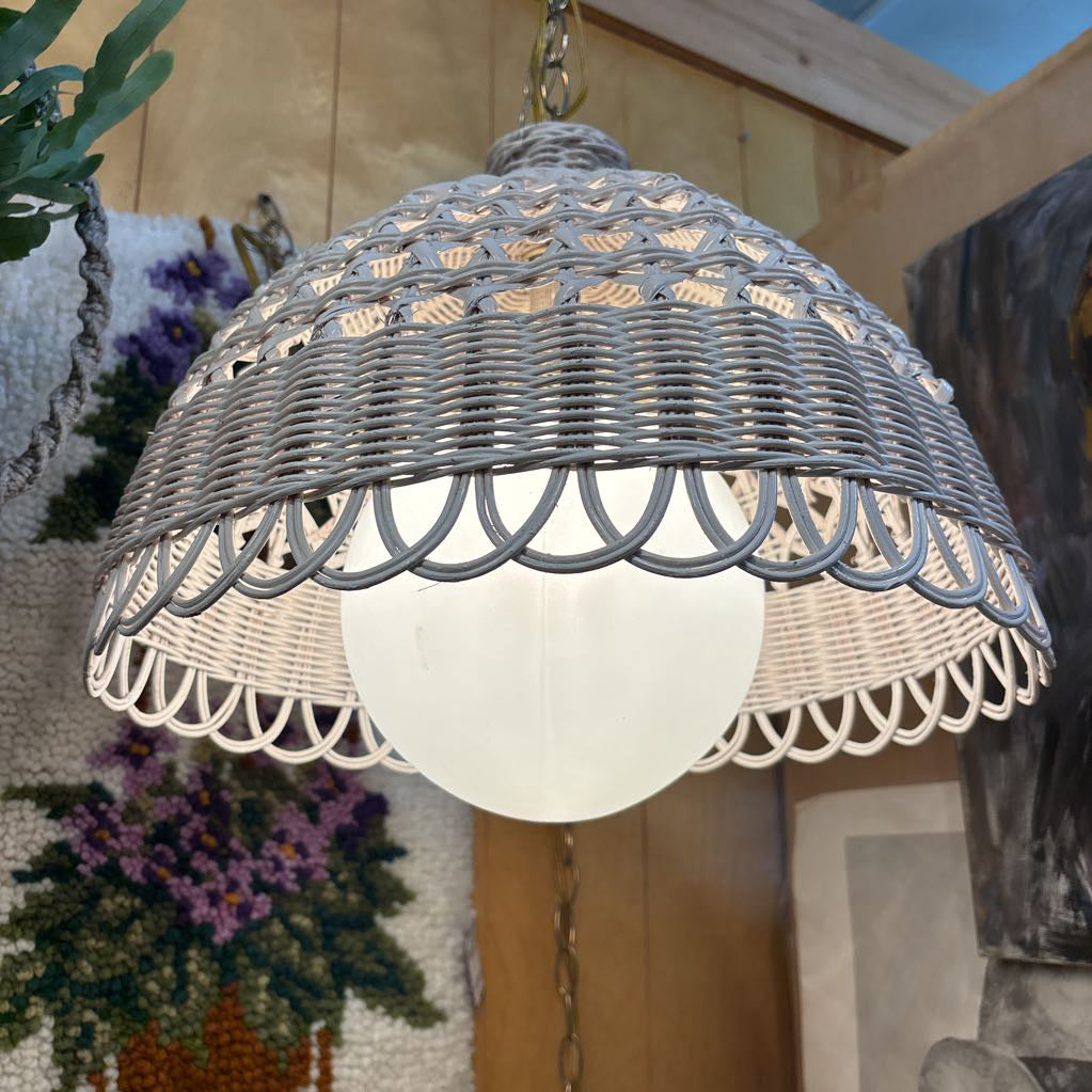 A white wicker shaded swag lamp hanging in a room setting.