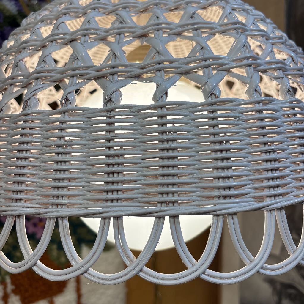 A white wicker shaded swag lamp hanging in a room setting.