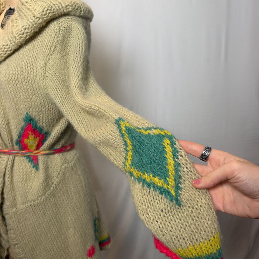A tan belted knit sweater hoodie on a mannequin in front of a white wall.