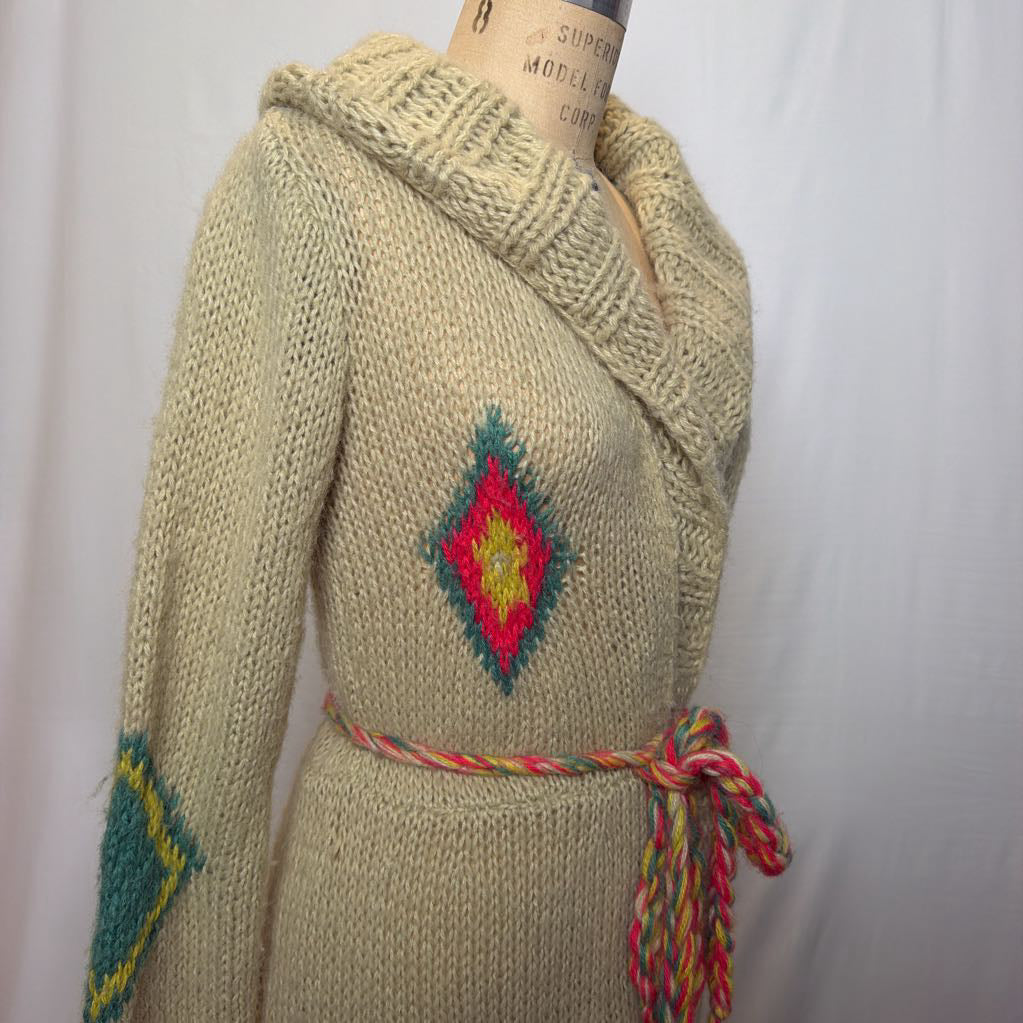A tan belted knit sweater hoodie on a mannequin in front of a white wall.