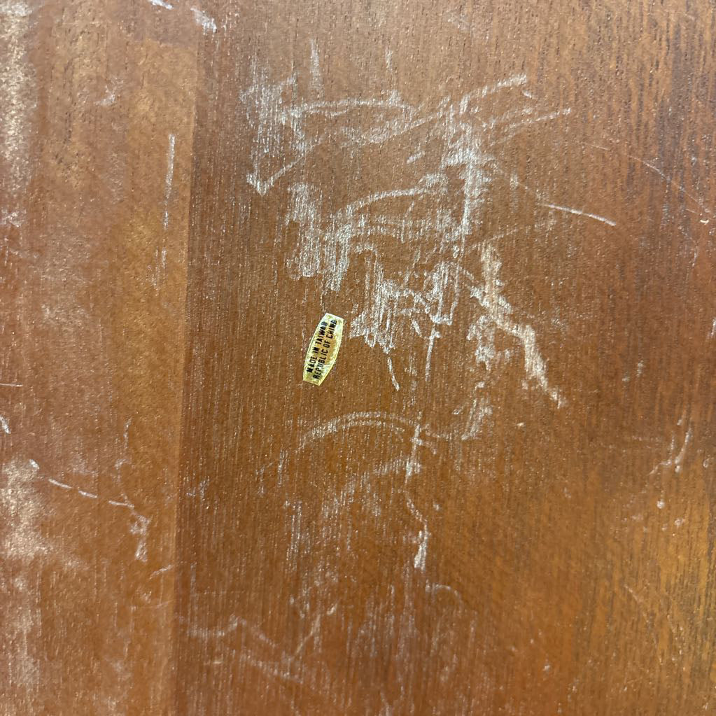 A sticker at the bottom of a scratched wooden surface that says, "Made in Taiwan."