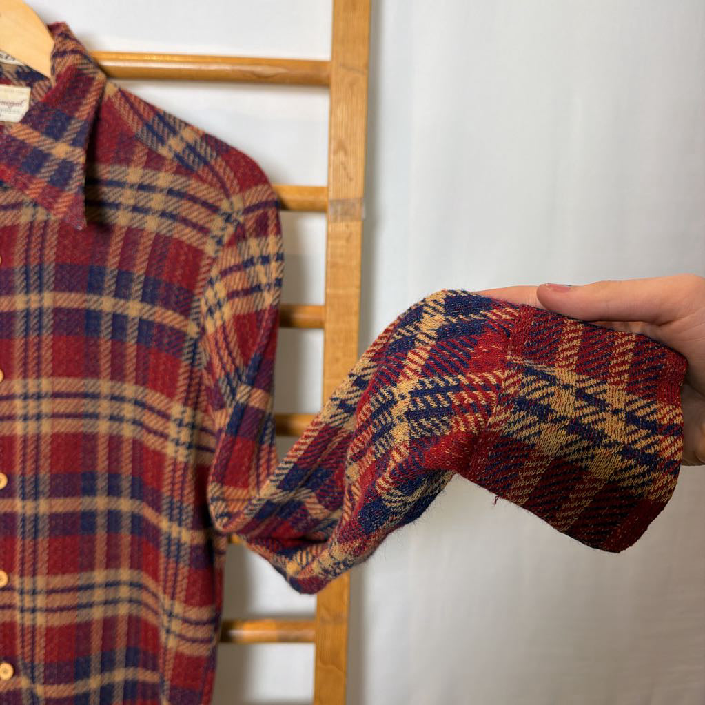 A button-up plaid shirt on a wooden rack.