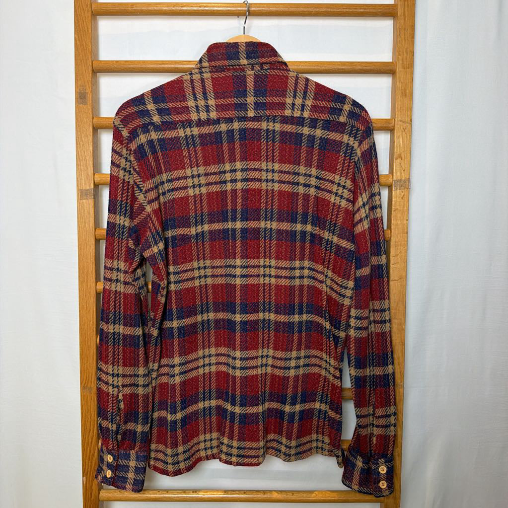 A button-up plaid shirt on a wooden rack.