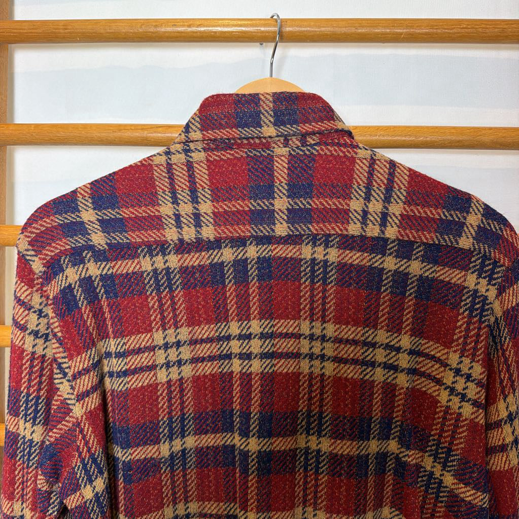 A button-up plaid shirt on a wooden rack.
