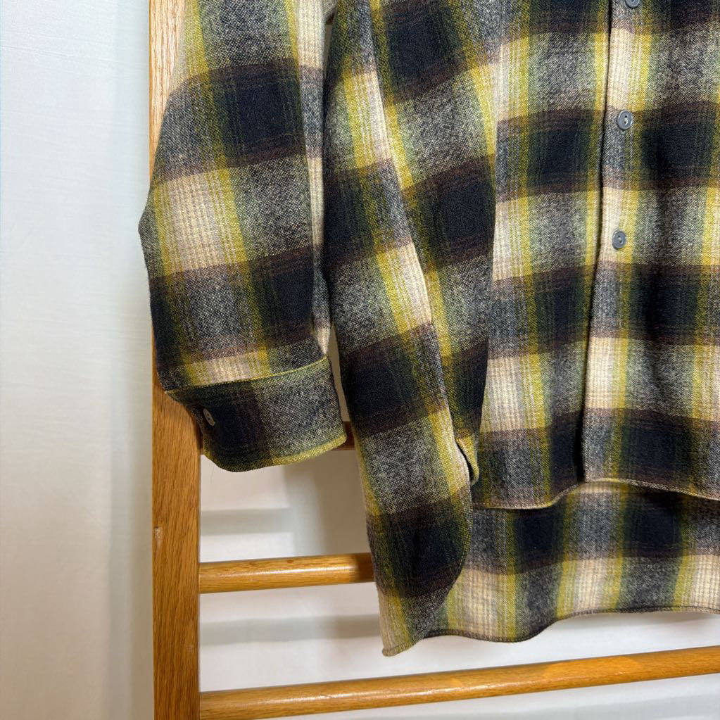 A green ombre plaid button-up shirt on a wooden rack.