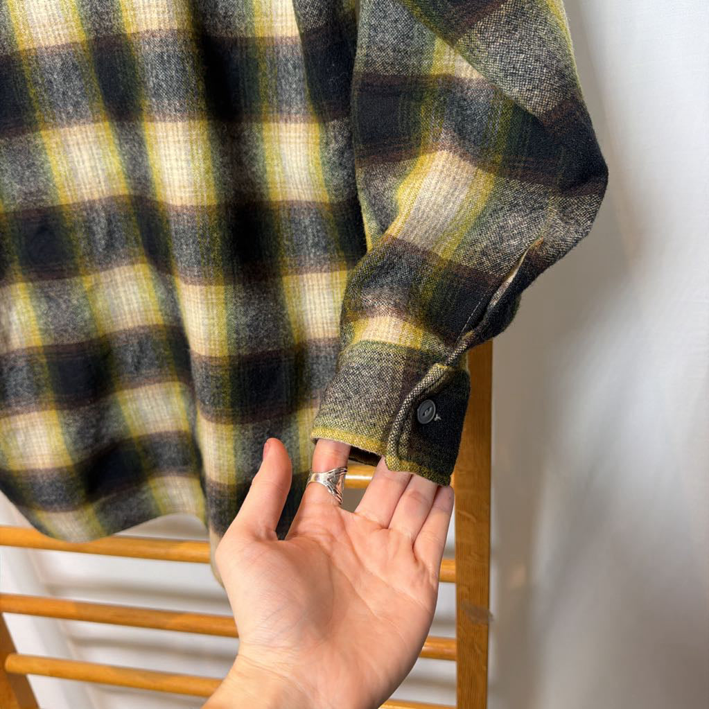 A green ombre plaid button-up shirt on a wooden rack.