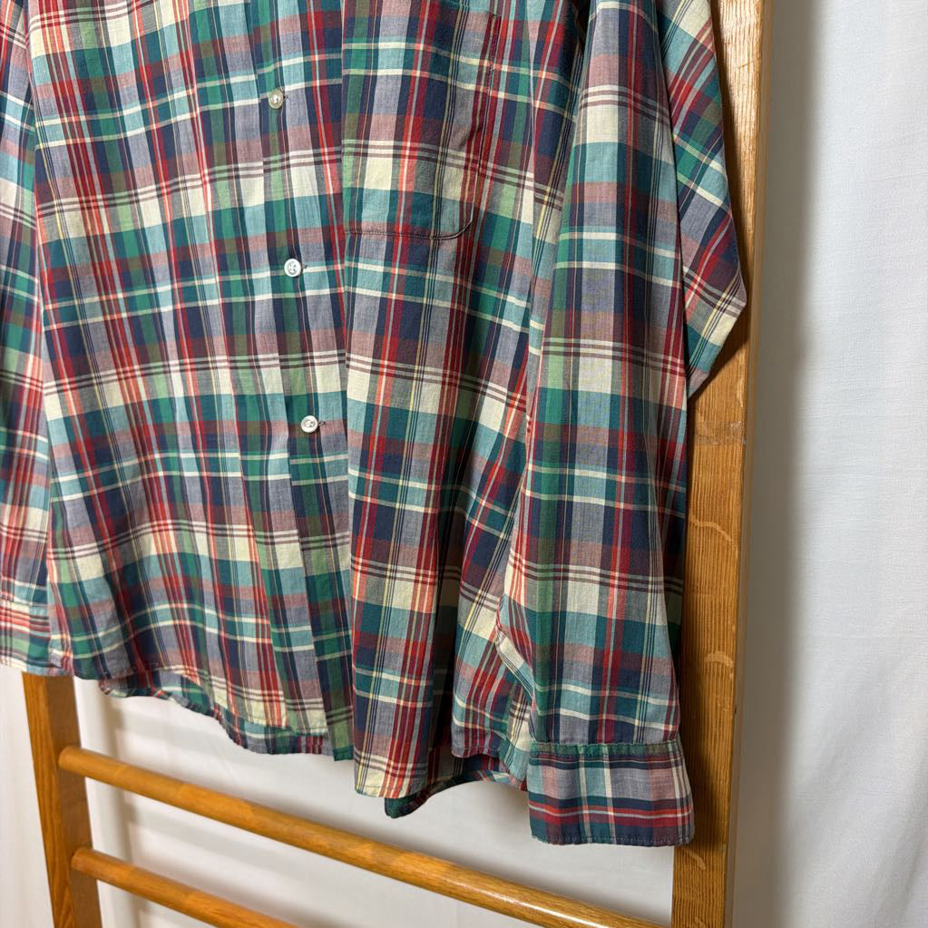 A plaid button-up shirt on a wooden rack.
