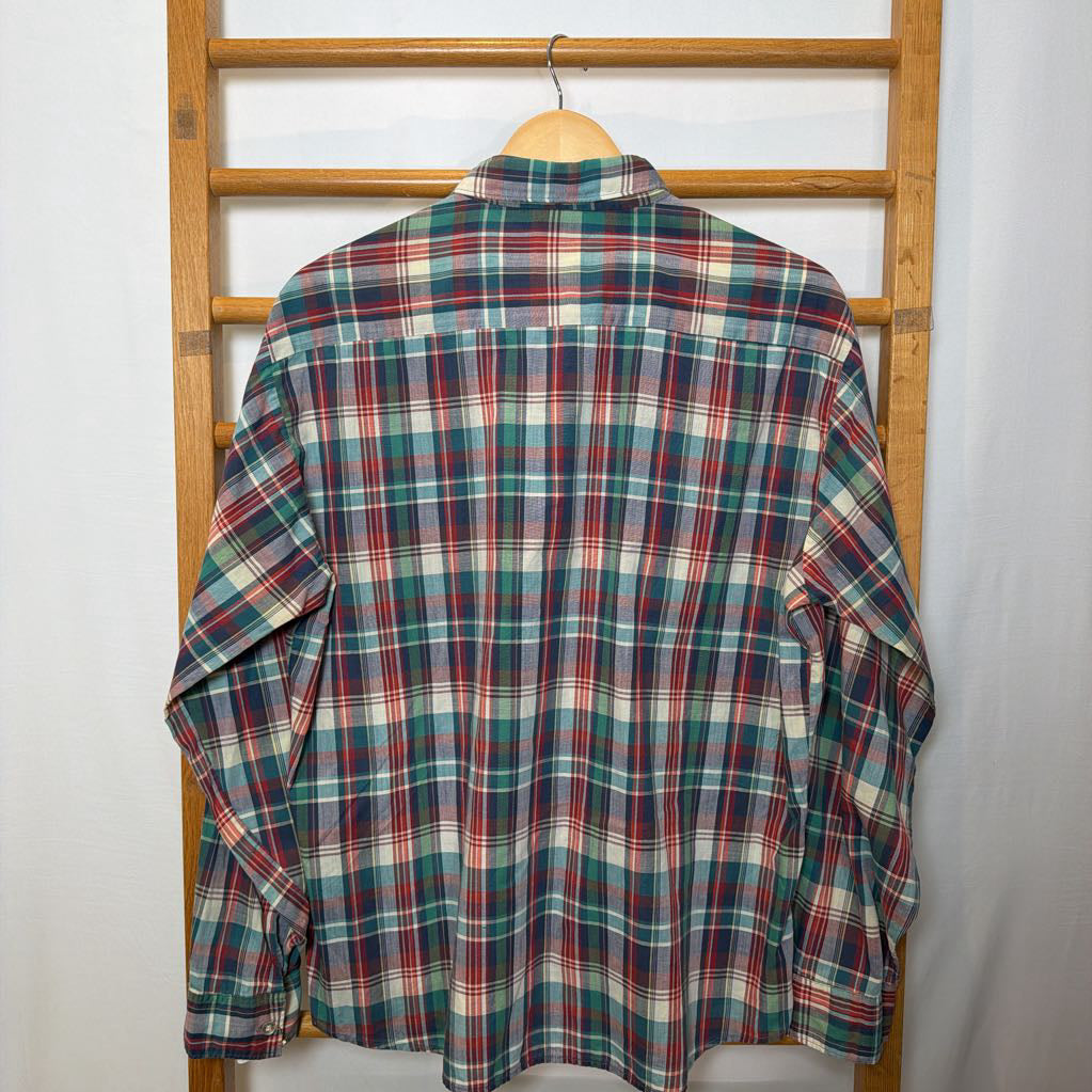 A plaid button-up shirt on a wooden rack.