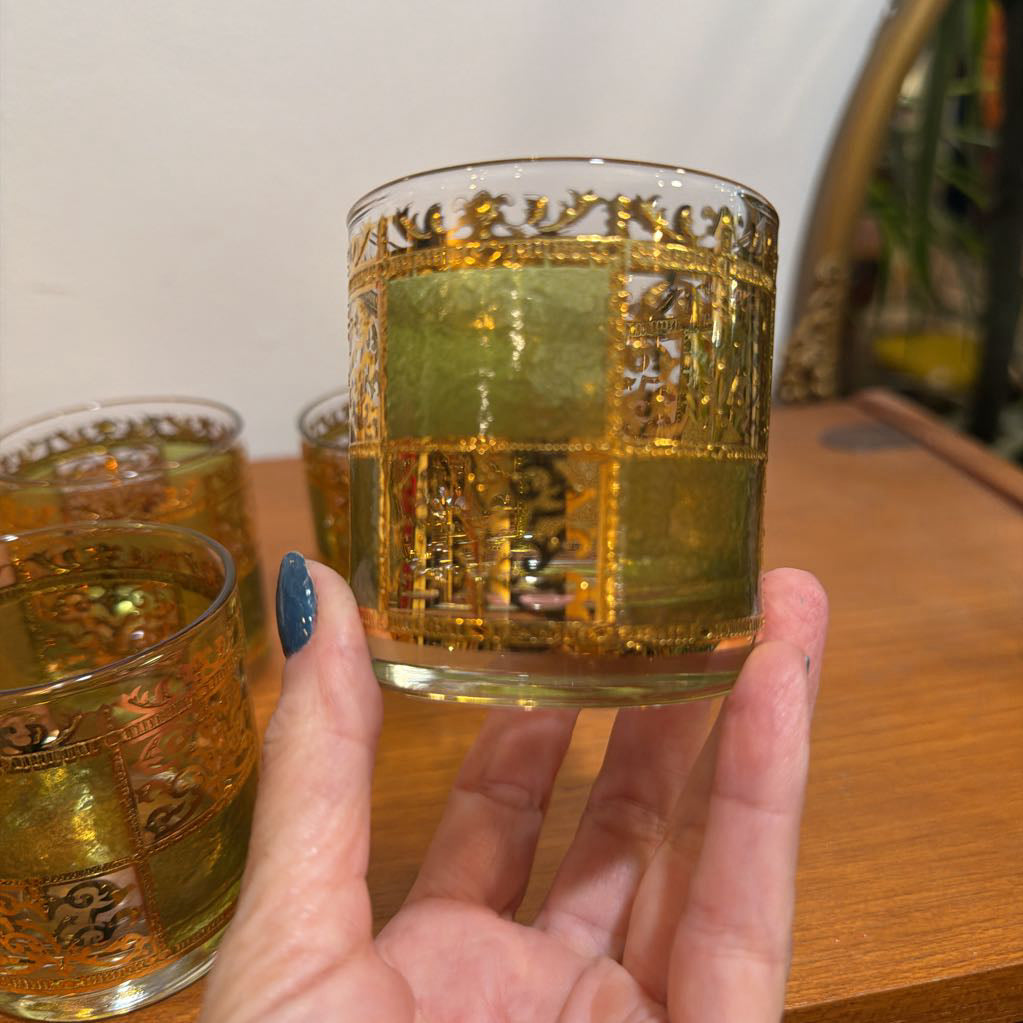 One culver prado green glassware featuring a pale green tine and ornate 22k gold filigree checkerboard panels being held in hand