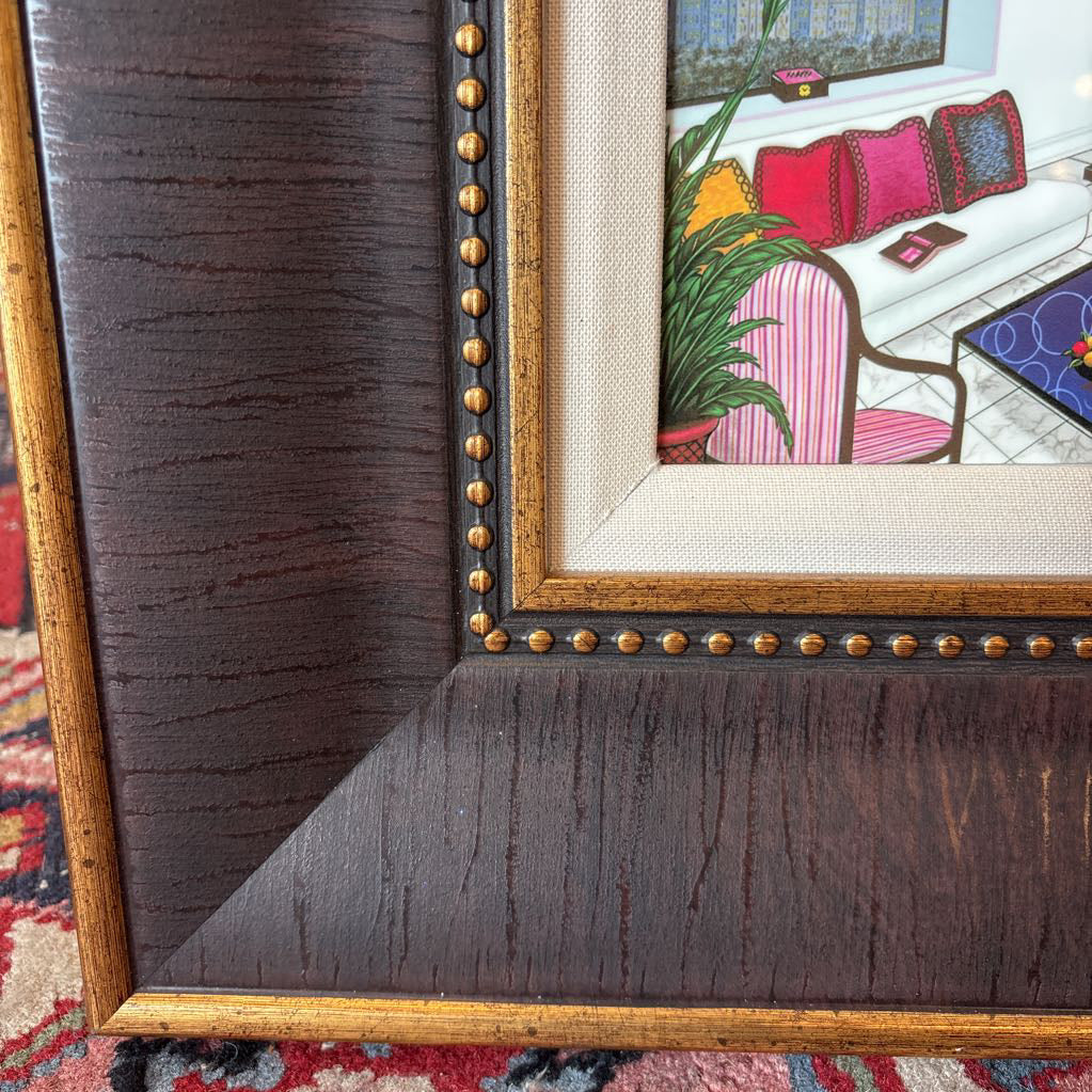 A framed artwork of a room and a nigh time cityscape outside of the windows.