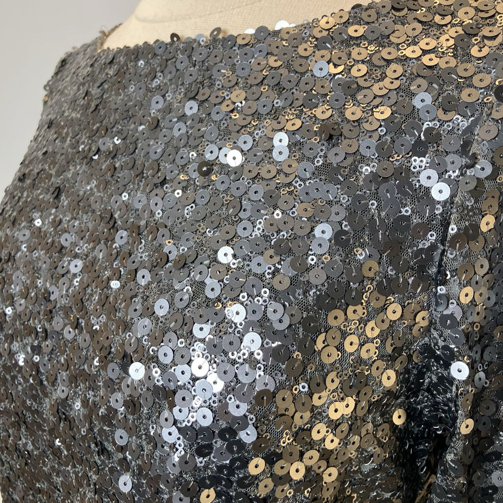Close-up of a sequined fabric with silver and gold sequins on a mannequin.