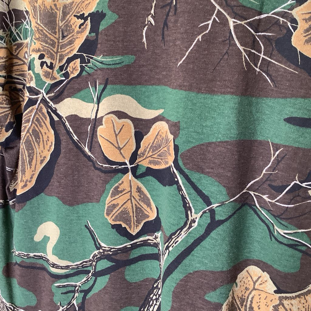 Close-up of a fabric with a nature-themed pattern featuring leaves and branches.