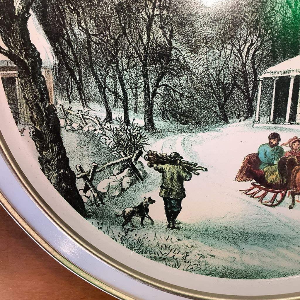 Decorative plate with a winter scene of people and animals in a snowy landscape.