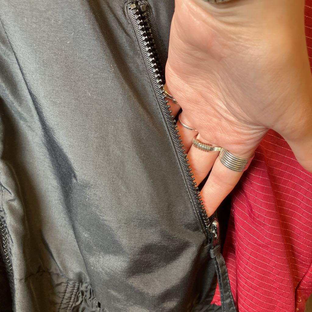 Hand with rings zipping a gray jacket