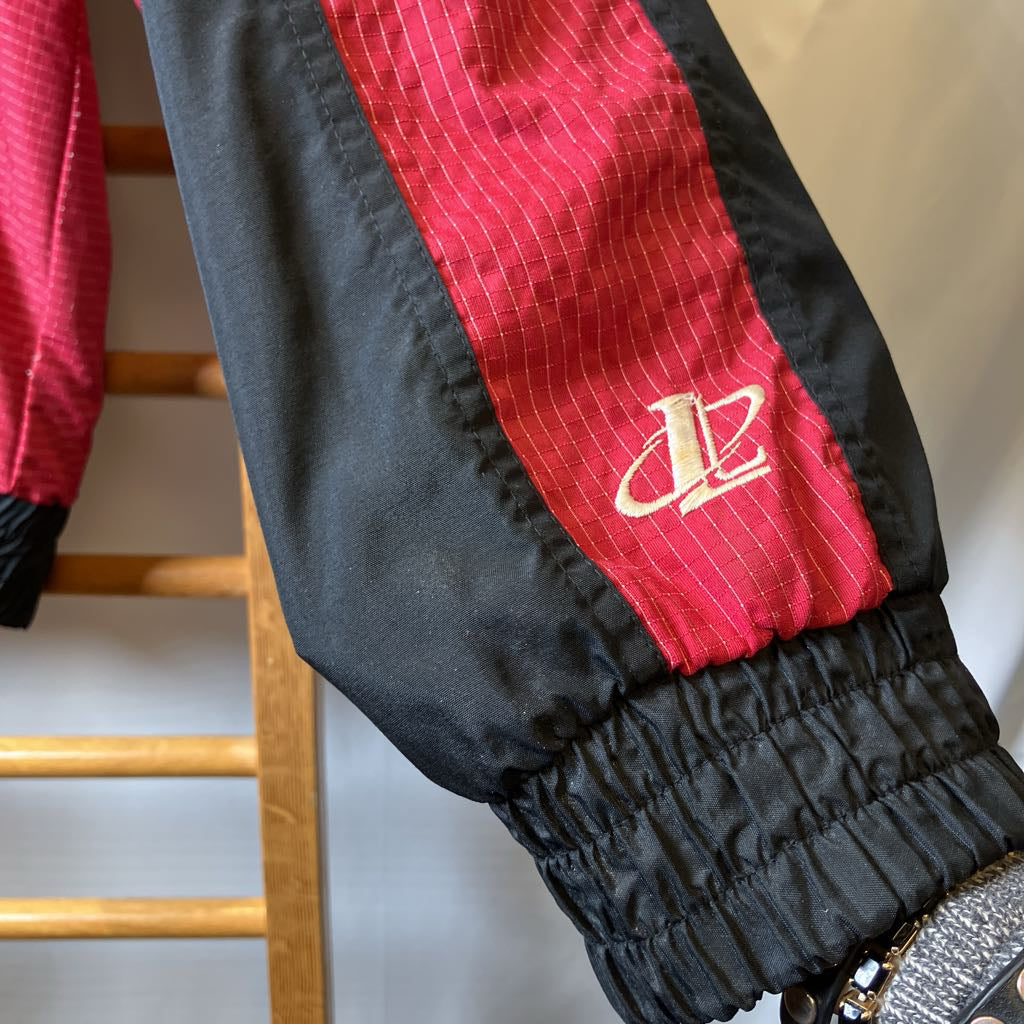 Black jacket sleeve with red stripe and logo on a wooden rack