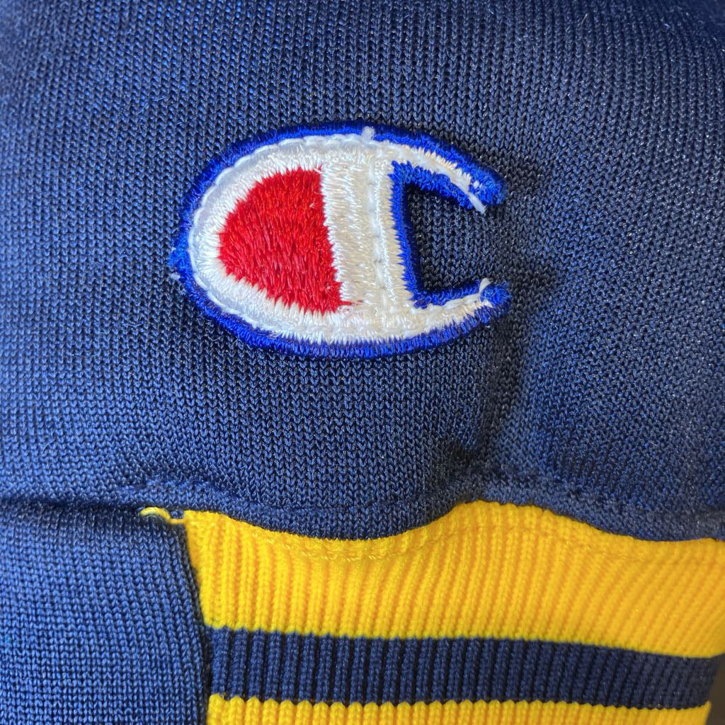 Close-up of a blue sweater with a Champion logo and yellow trim.