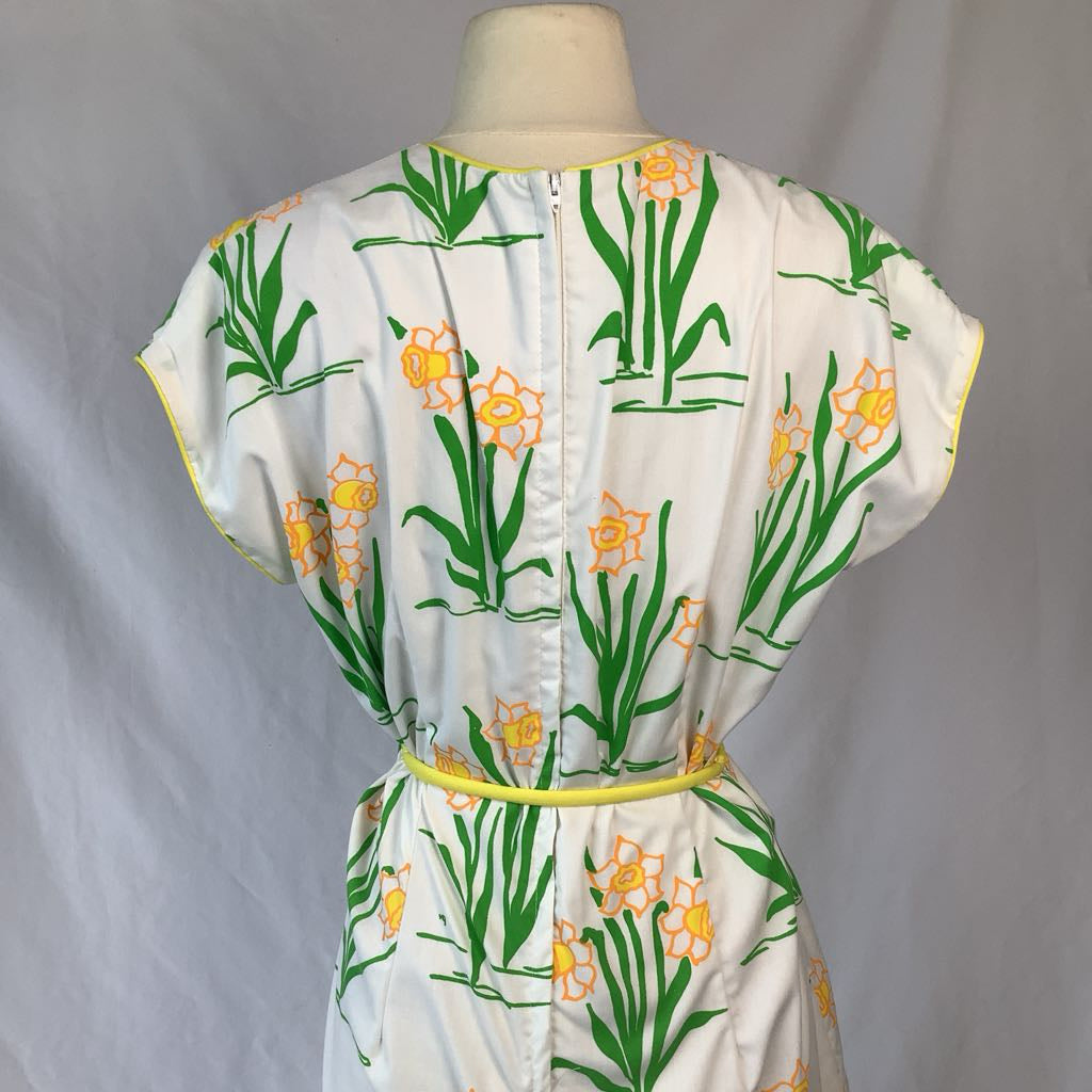 White dress with green floral pattern on a mannequin against a gray background