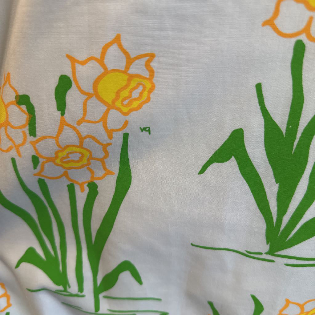 White fabric with yellow daffodil flowers and green leaves printed on it.